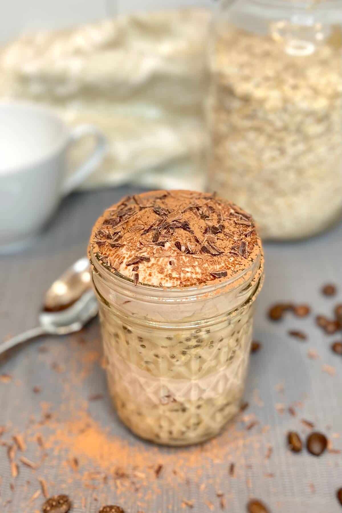 Tiramisu oats in a mason jar, sprinkled with cocoa and chocolate shavings on top.