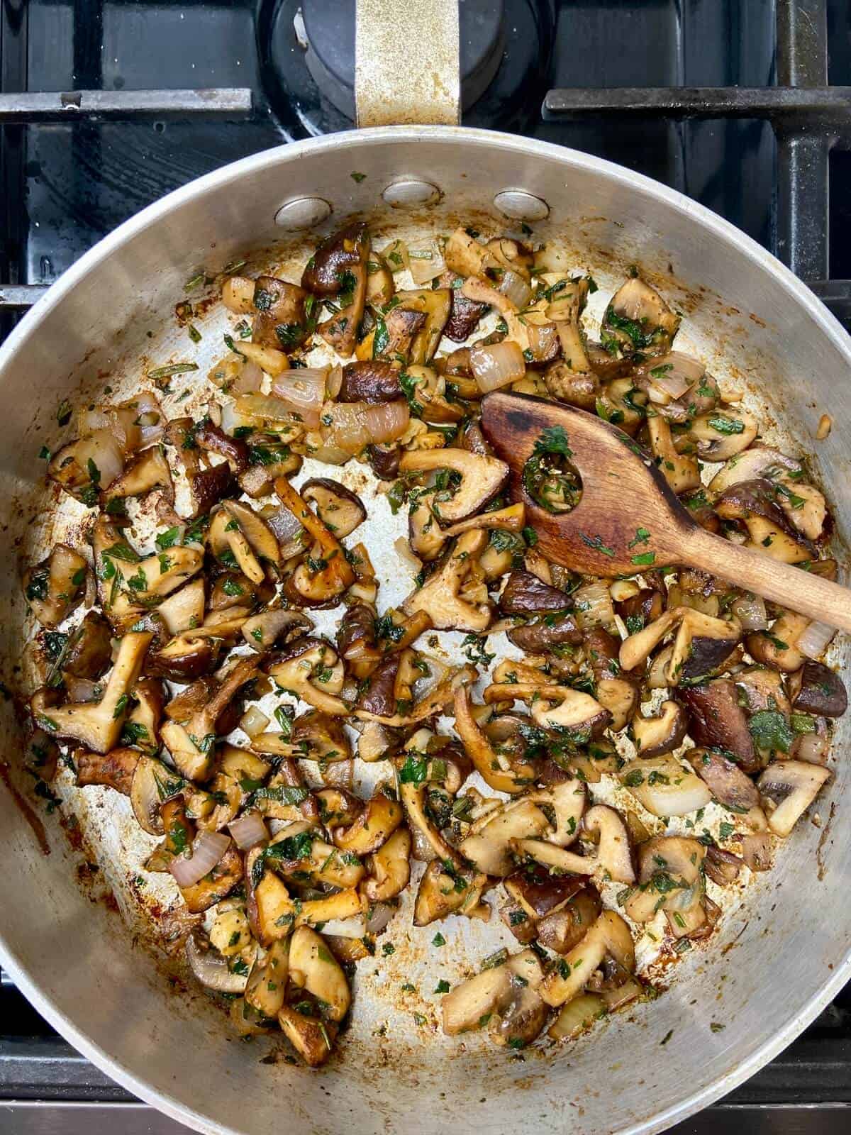 Mushrooms, shallots, and herbs sauteing in pan.