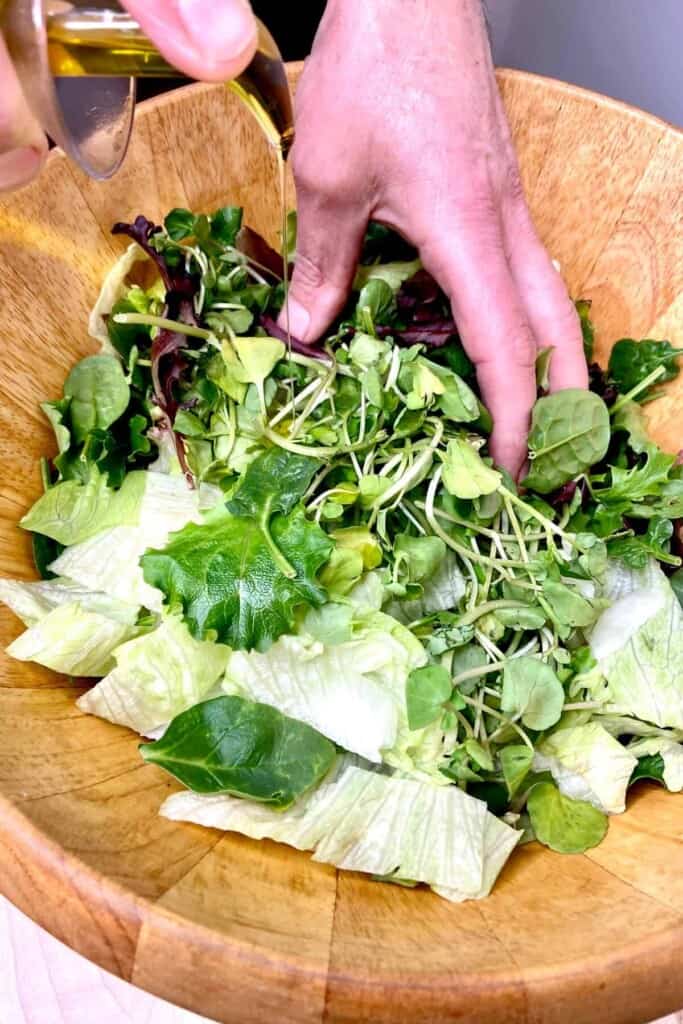 Adding olive oil to mixed lettuce leaves