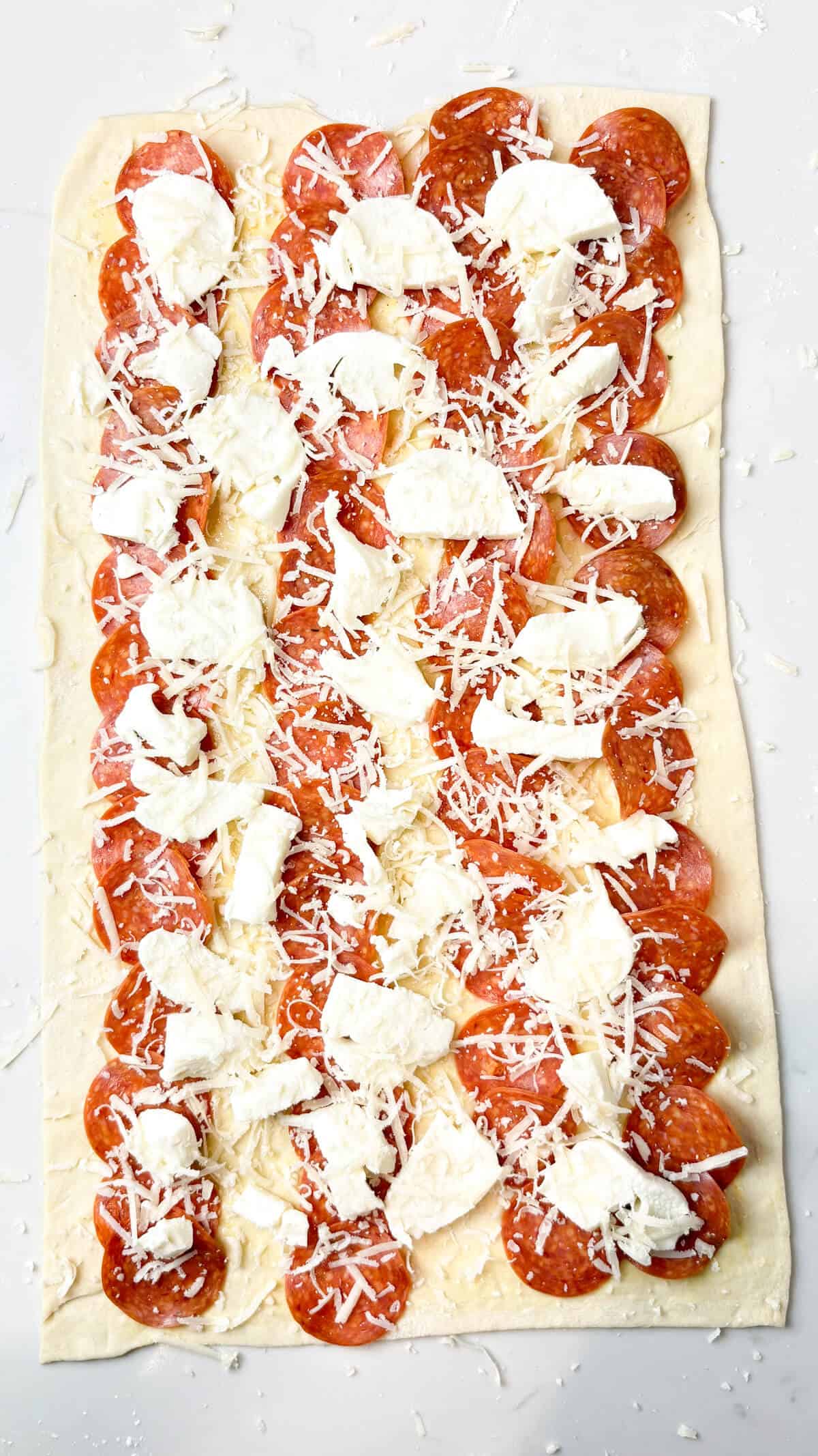 Pepperoni, mozzarella, and parmesan layered on dough.