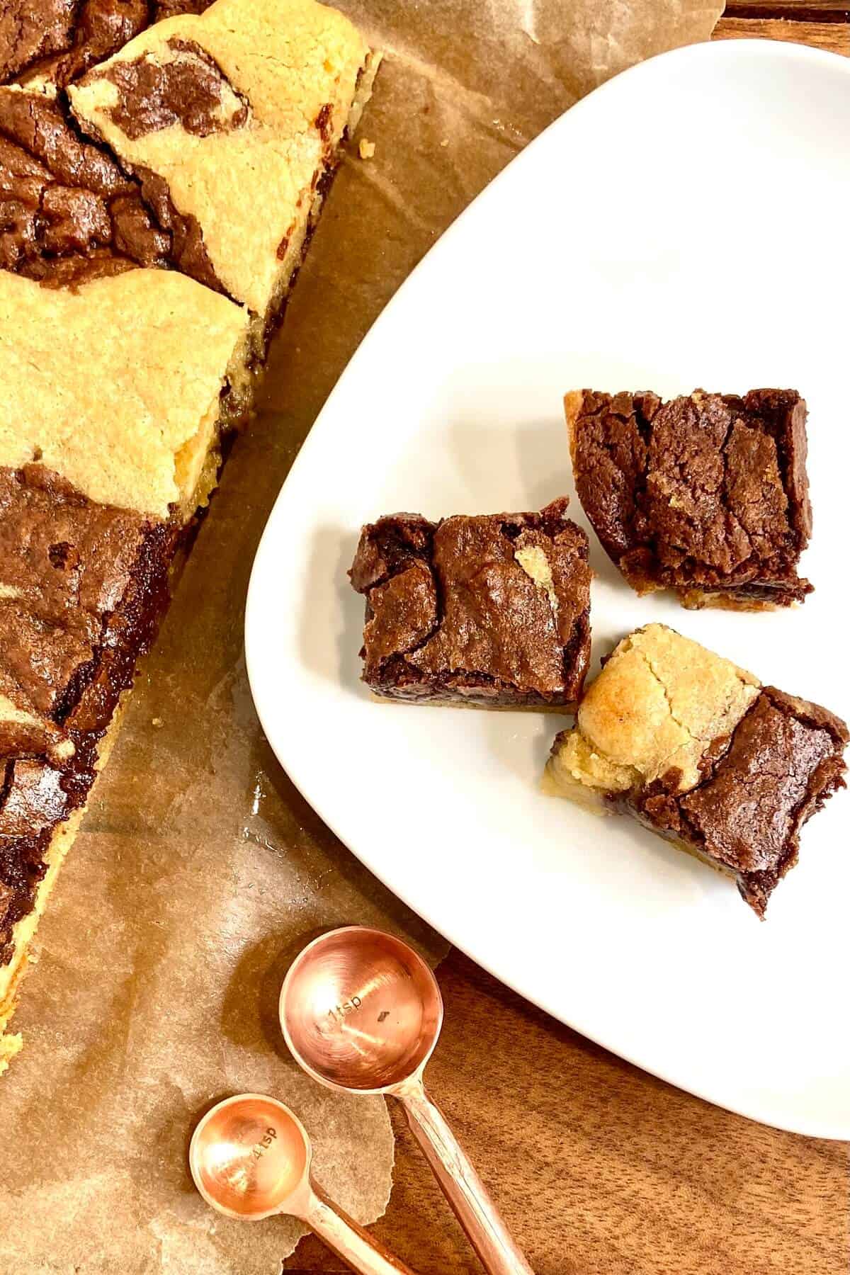 Three brownies on a plate, on a parchment lined table.