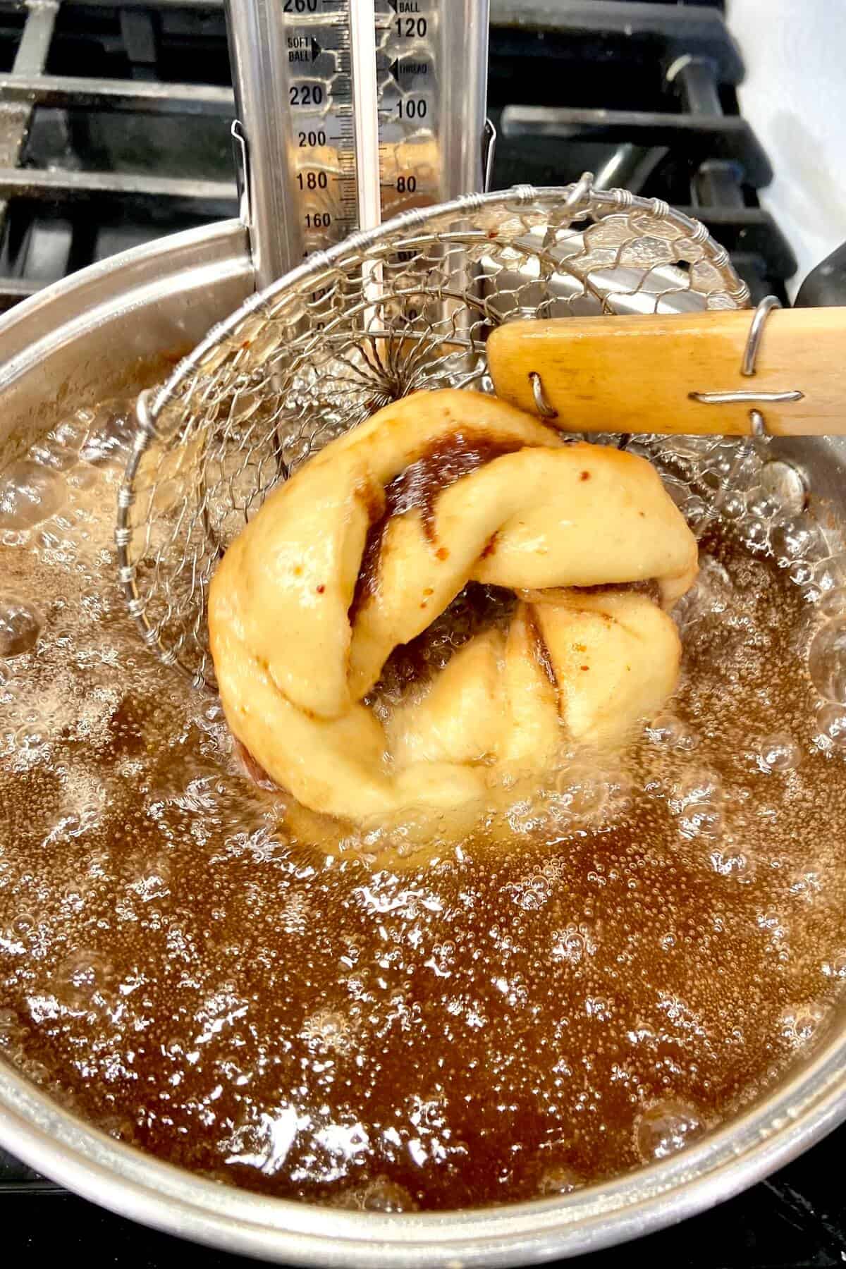 Turning the donut over, while it's frying in oil.