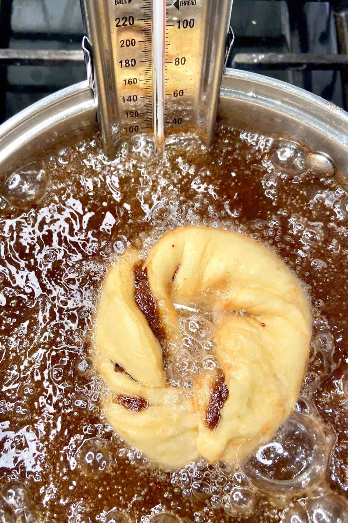 Placing donut in oil.