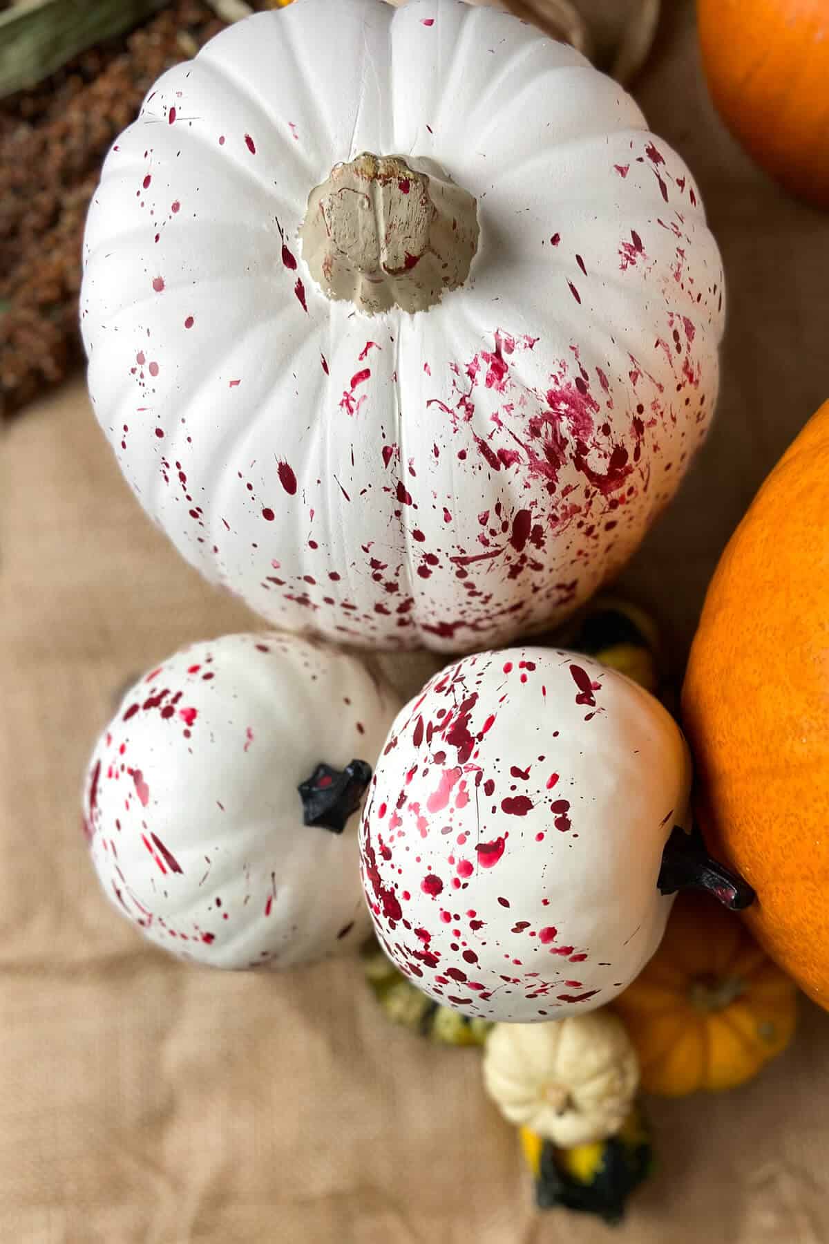 One large and two small splatter pumpkins on a table