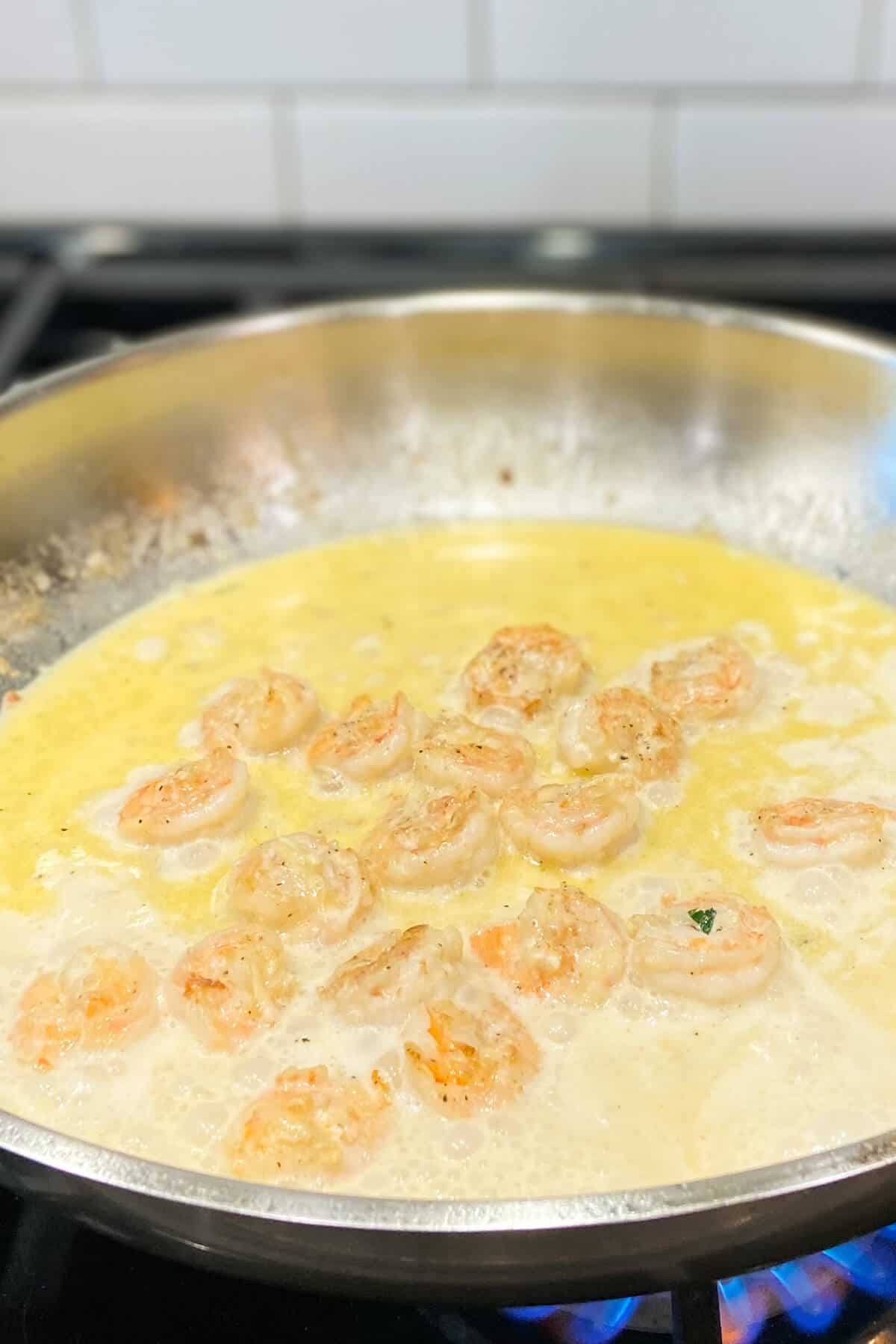 Shrimp cooking in pan with butter and olive oil.