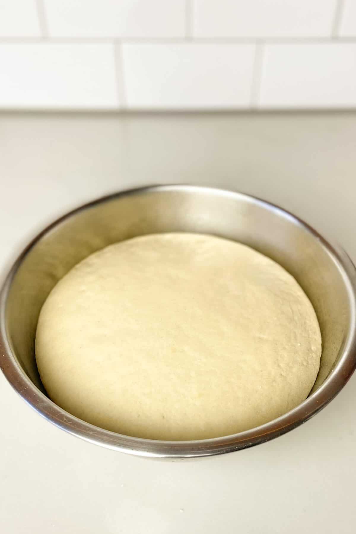 Dough in stainless steel bowl has doubled in size.