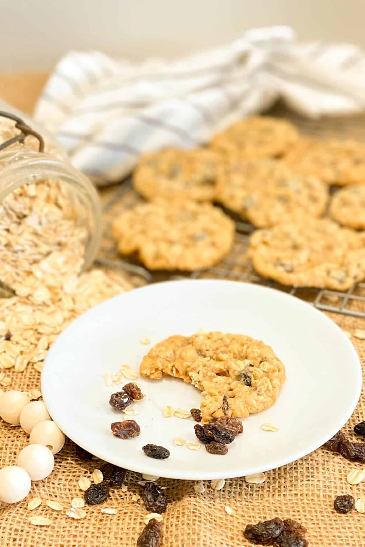 Cookie on a plate, with more on cooling rack, and oats on table.