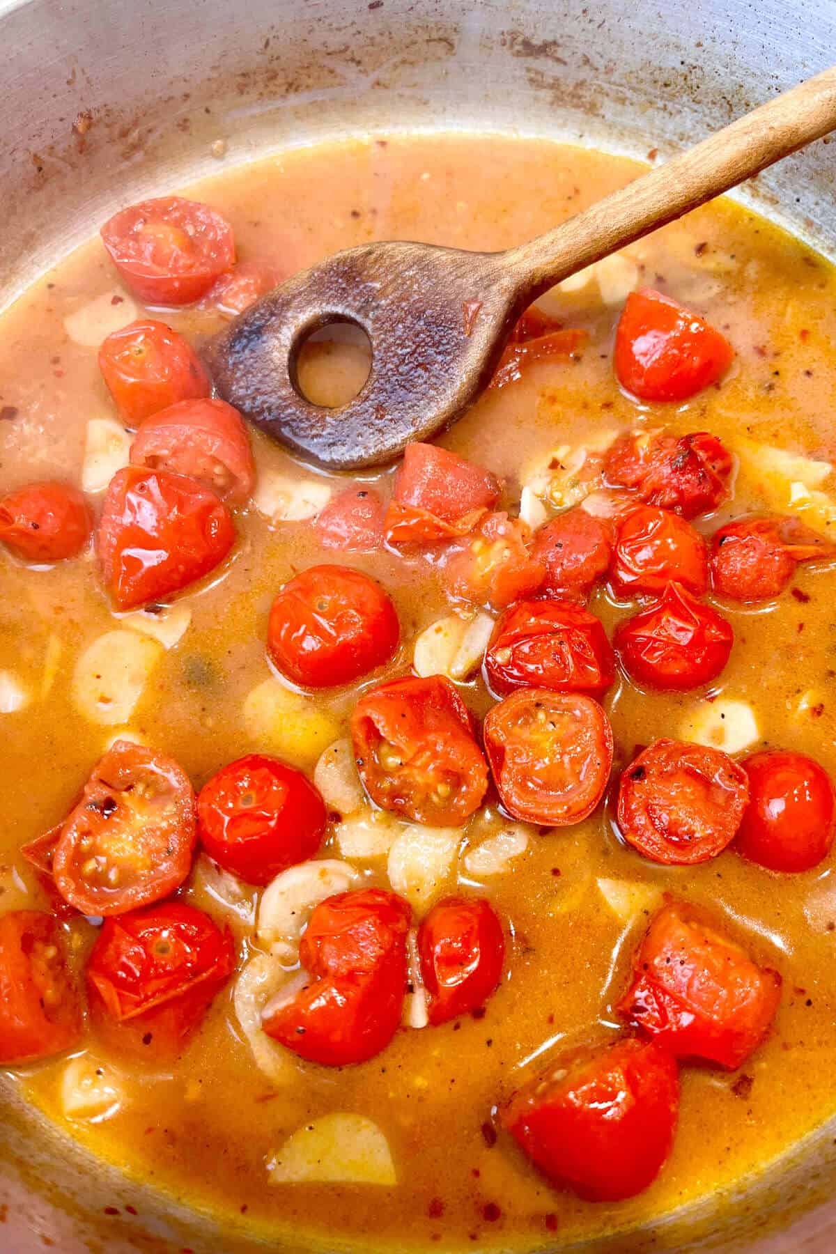 Tomatoes and clam juice cooking in pan.