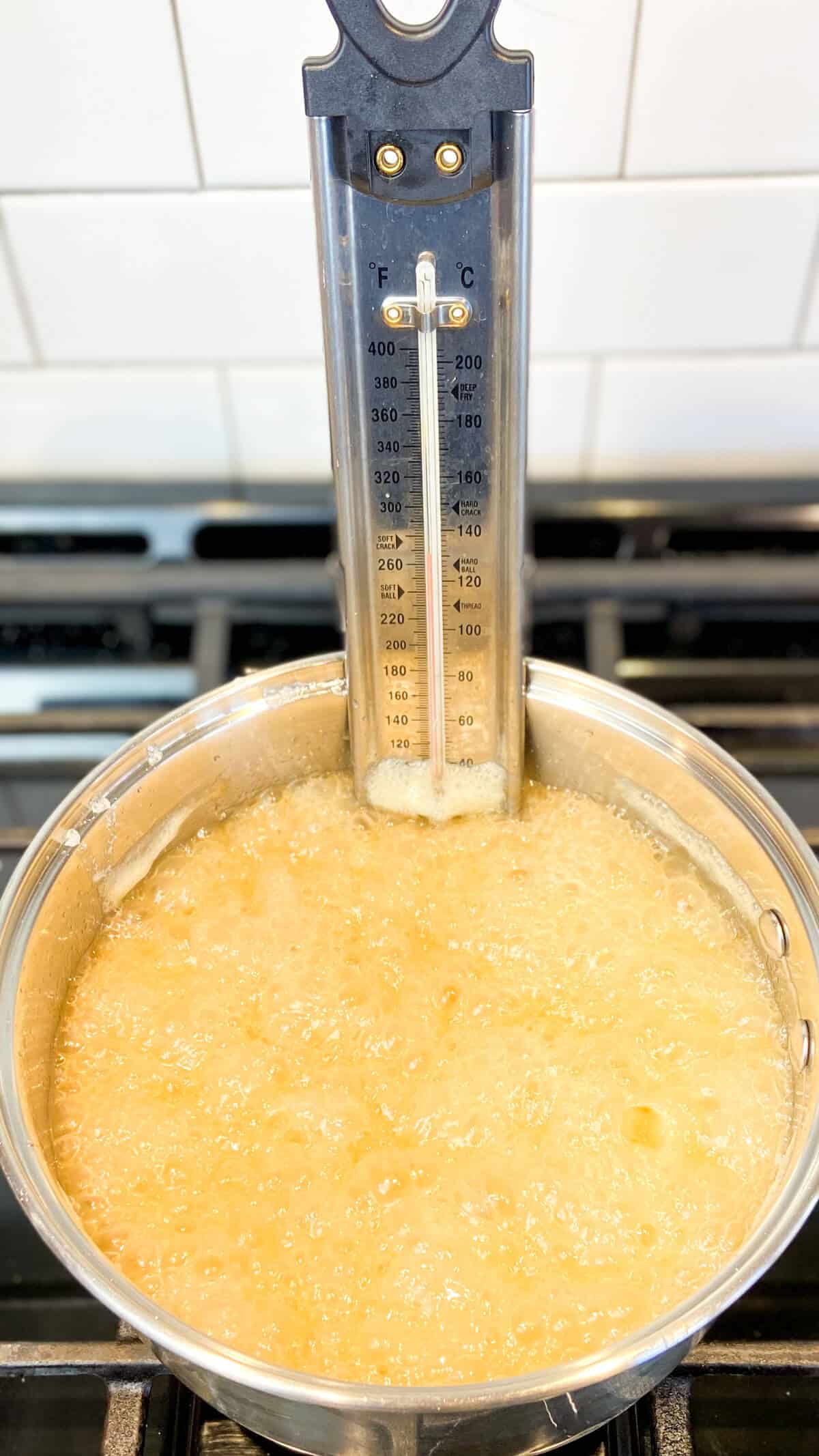 Candy thermometer in a pot while cooking the brittle mixture.