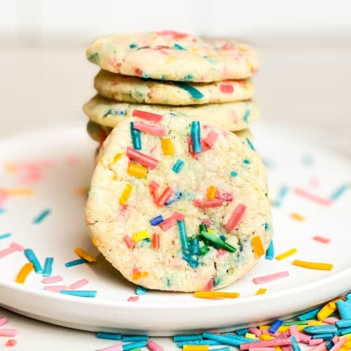 Sprinkle sugar cookies, piled high on a plate.