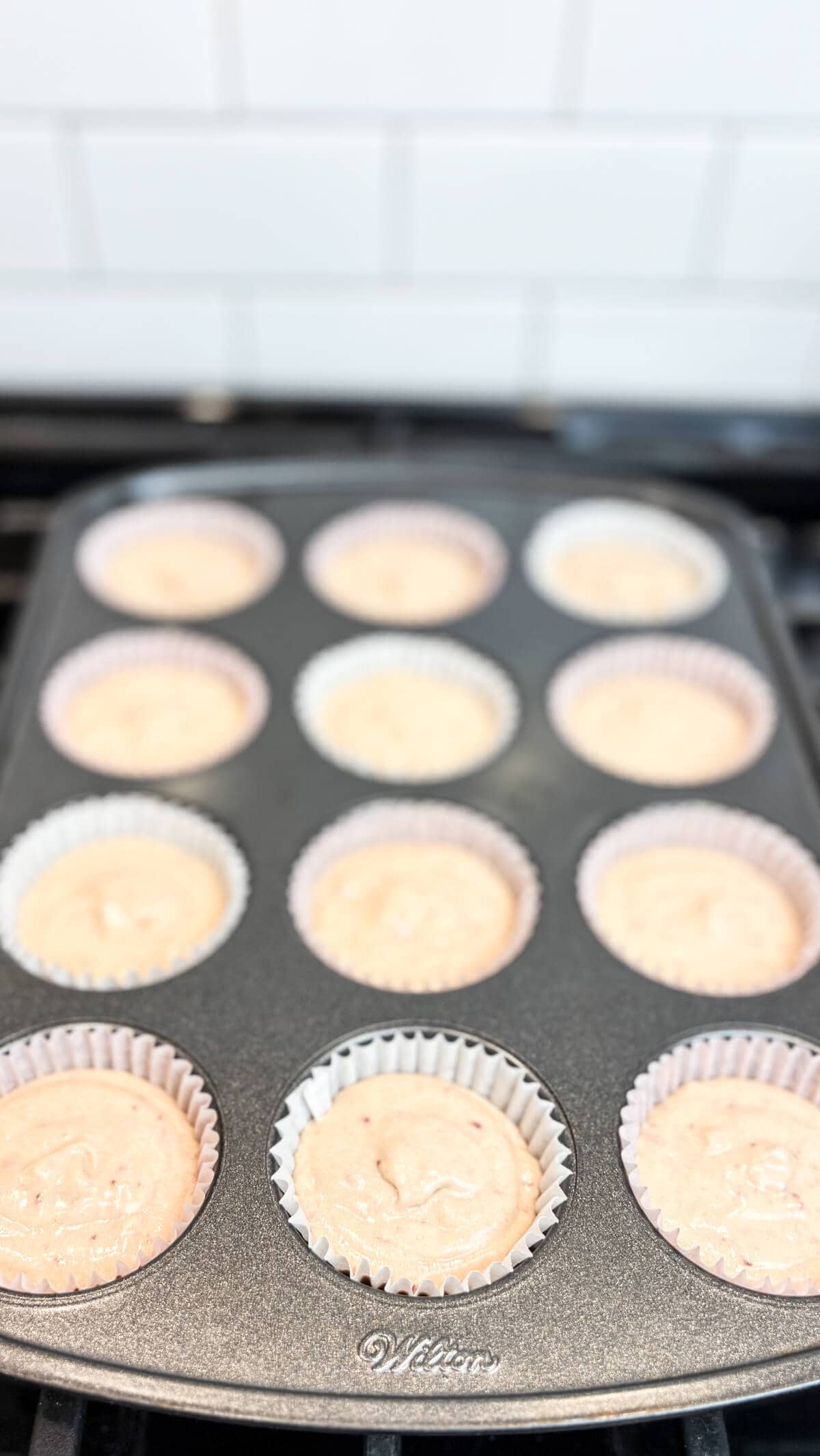 Cupcake batter in a lined muffin tin.
