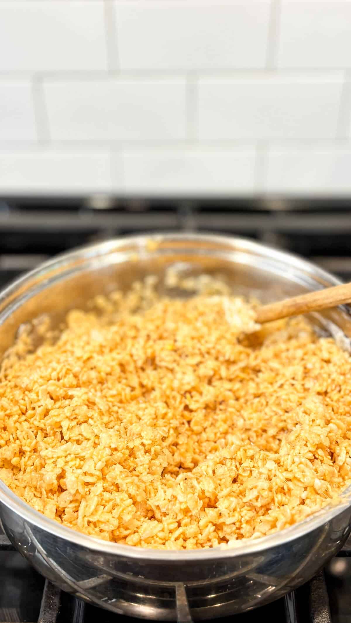 Stirring rice krispie cereal into the pan.