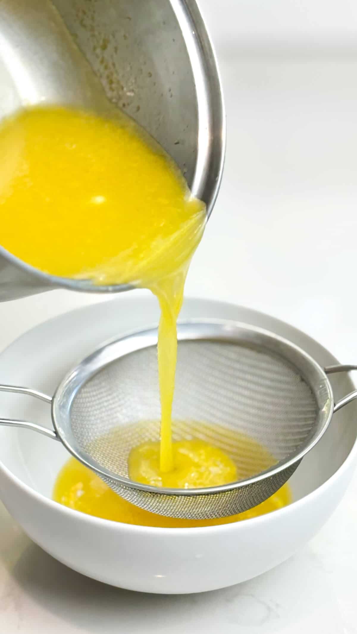 Pouring curd into a bowl through a fine mesh sieve.