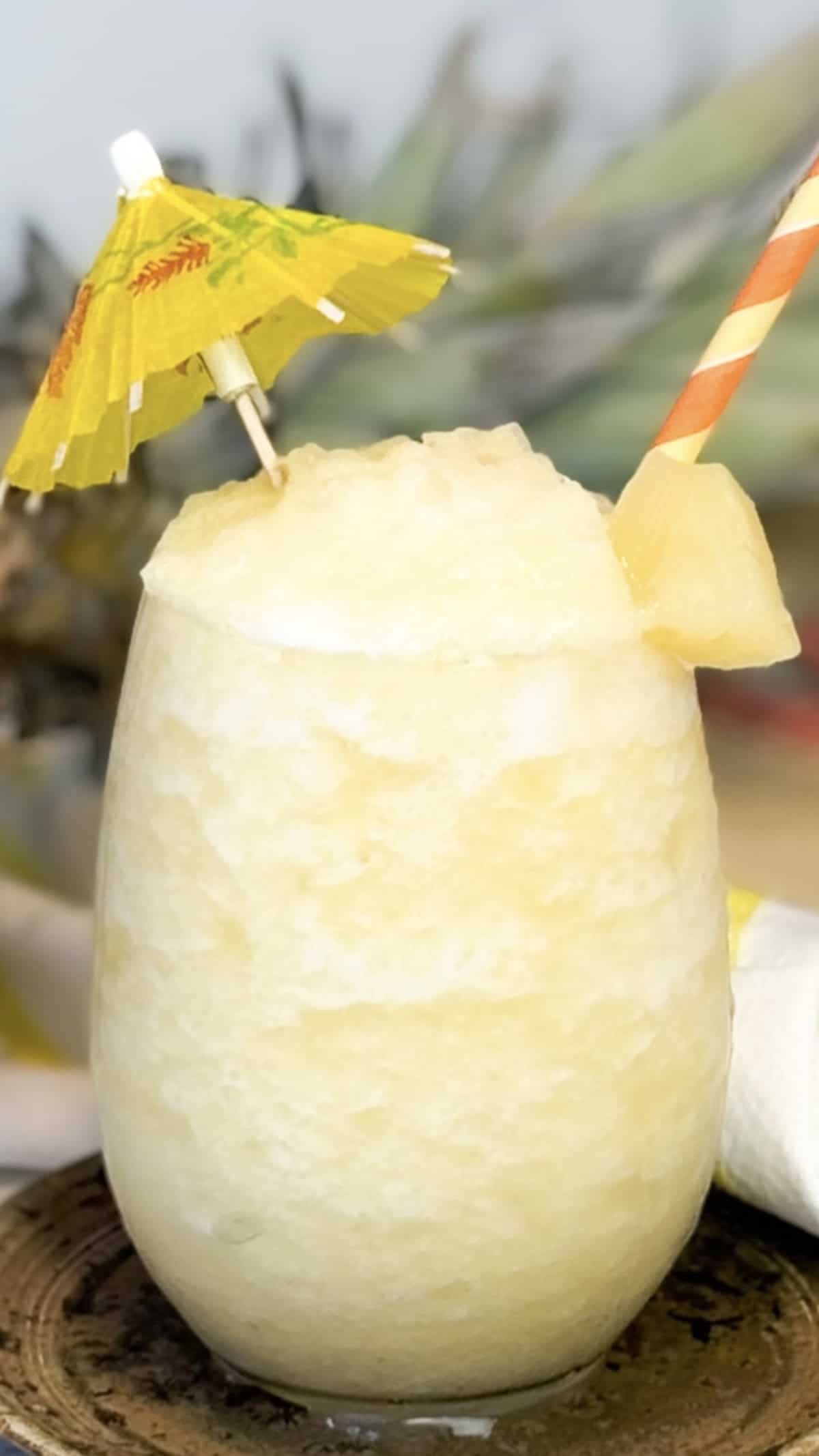 In a glass with a straw and decorative mini drink umbrella.