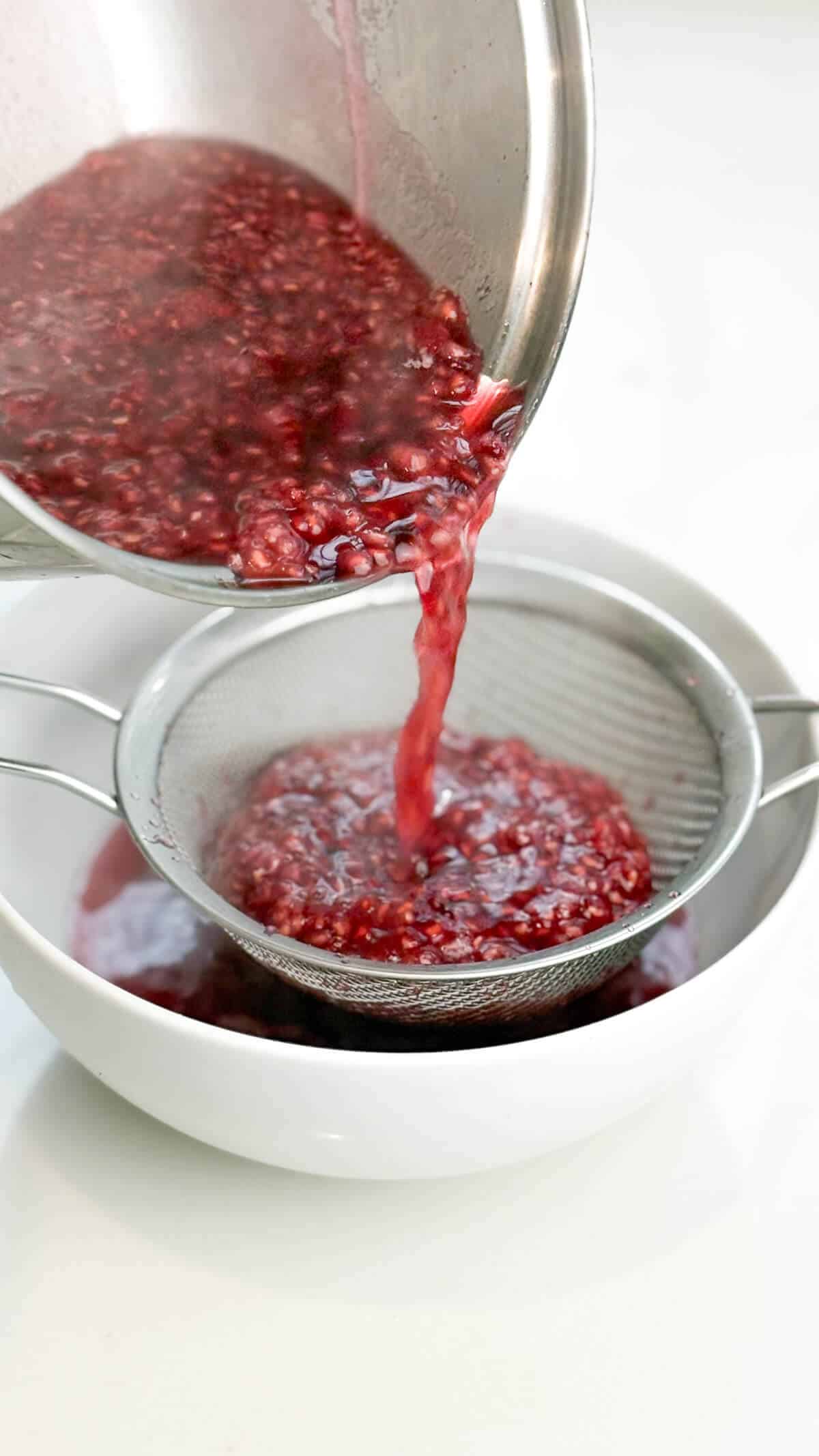 Pouring syrup into a bowl through a fine mesh sieve.