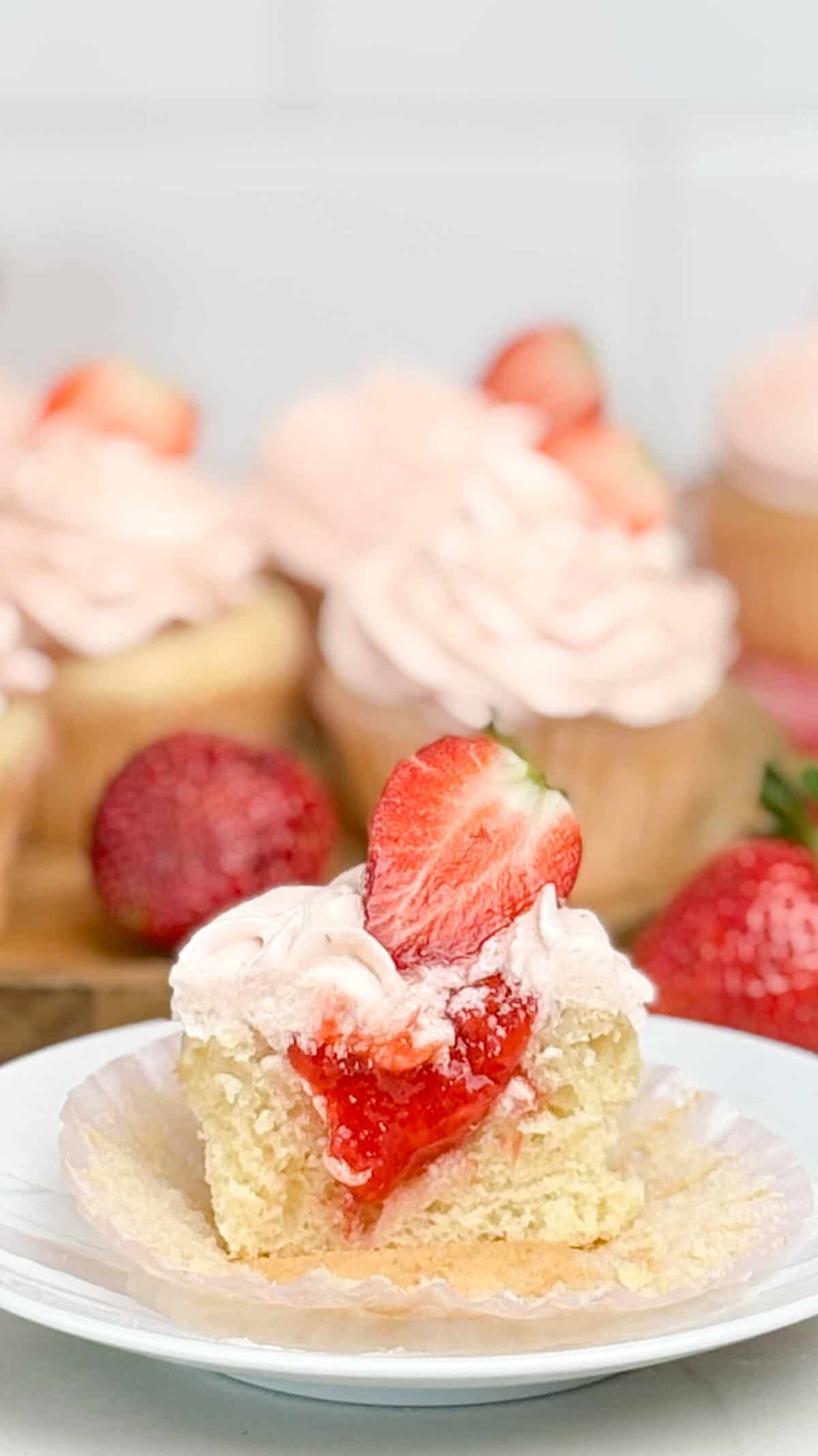 A cupcake cut in half, filled with fresh strawberry compote filling.