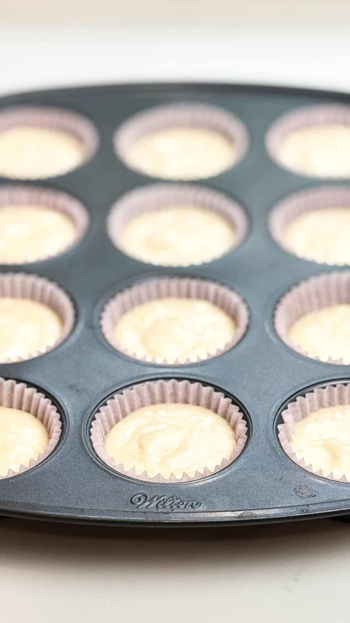 Lined muffin tin filled with cupcake batter.