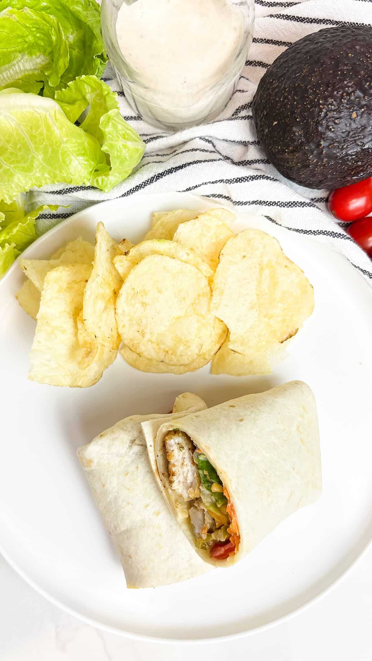 Wrap sandwich on plate with potato chips.