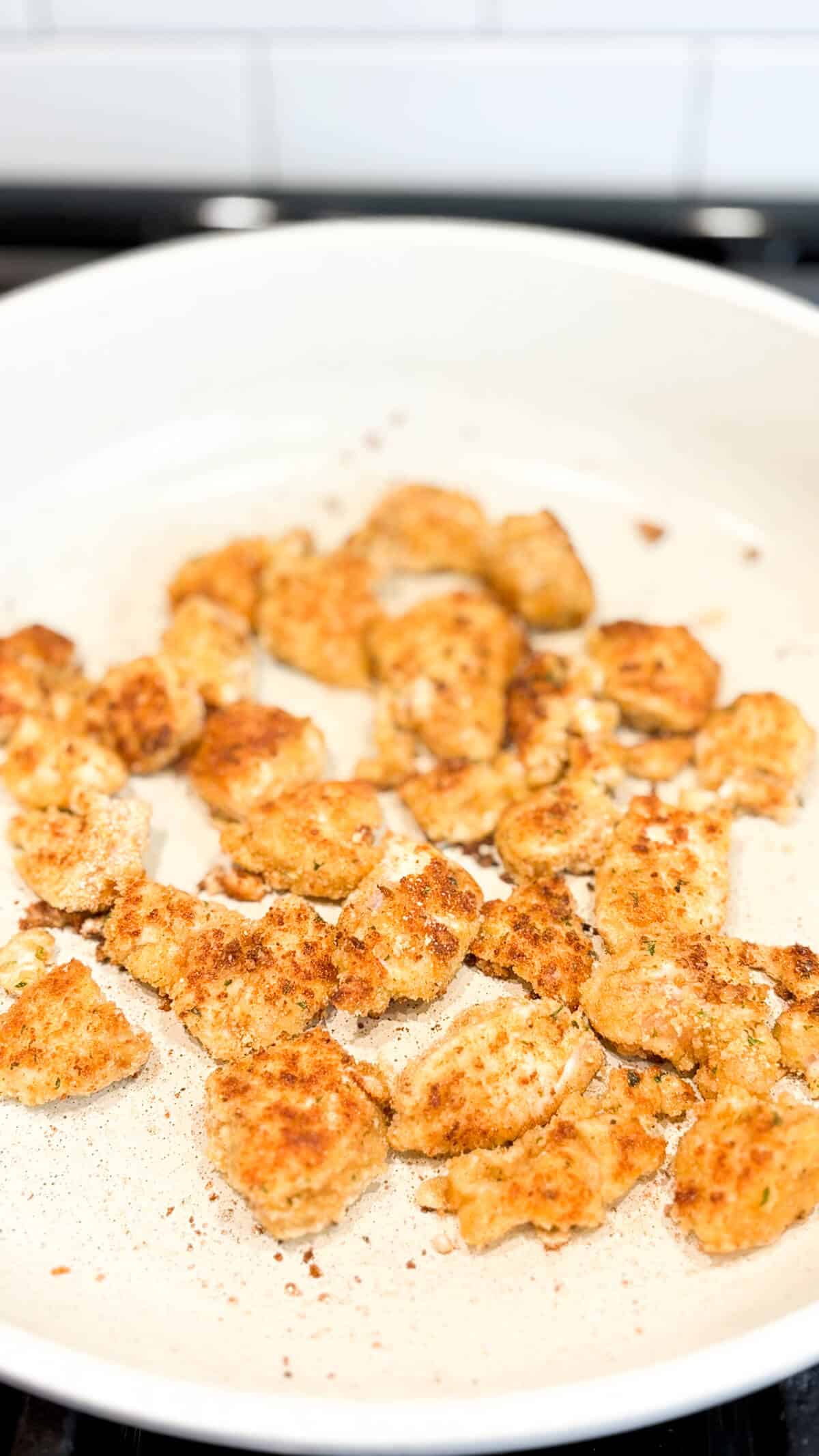 Cooking breaded chicken in a pan on the stove.
